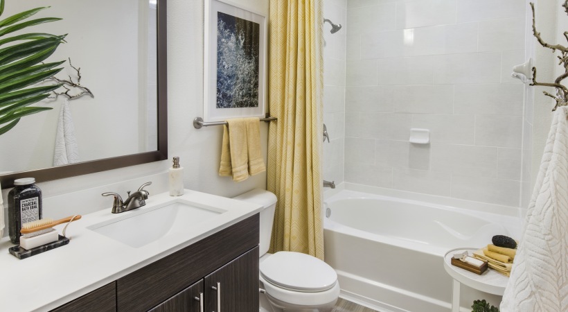 bathroom with white tiles an a yellow curtain and towels